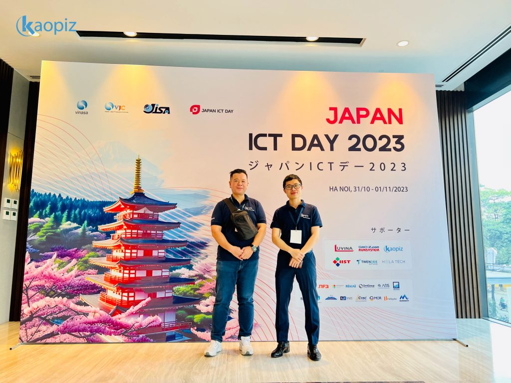 Photo of Kaopiz representatives and technology experts at Japan ICT Day 2023. Kaopiz members are standing on an event stage with the ICT Day banner visible in the background. The photo captures the collaborative spirit at the event with attendees smiling and engaged in discussion."