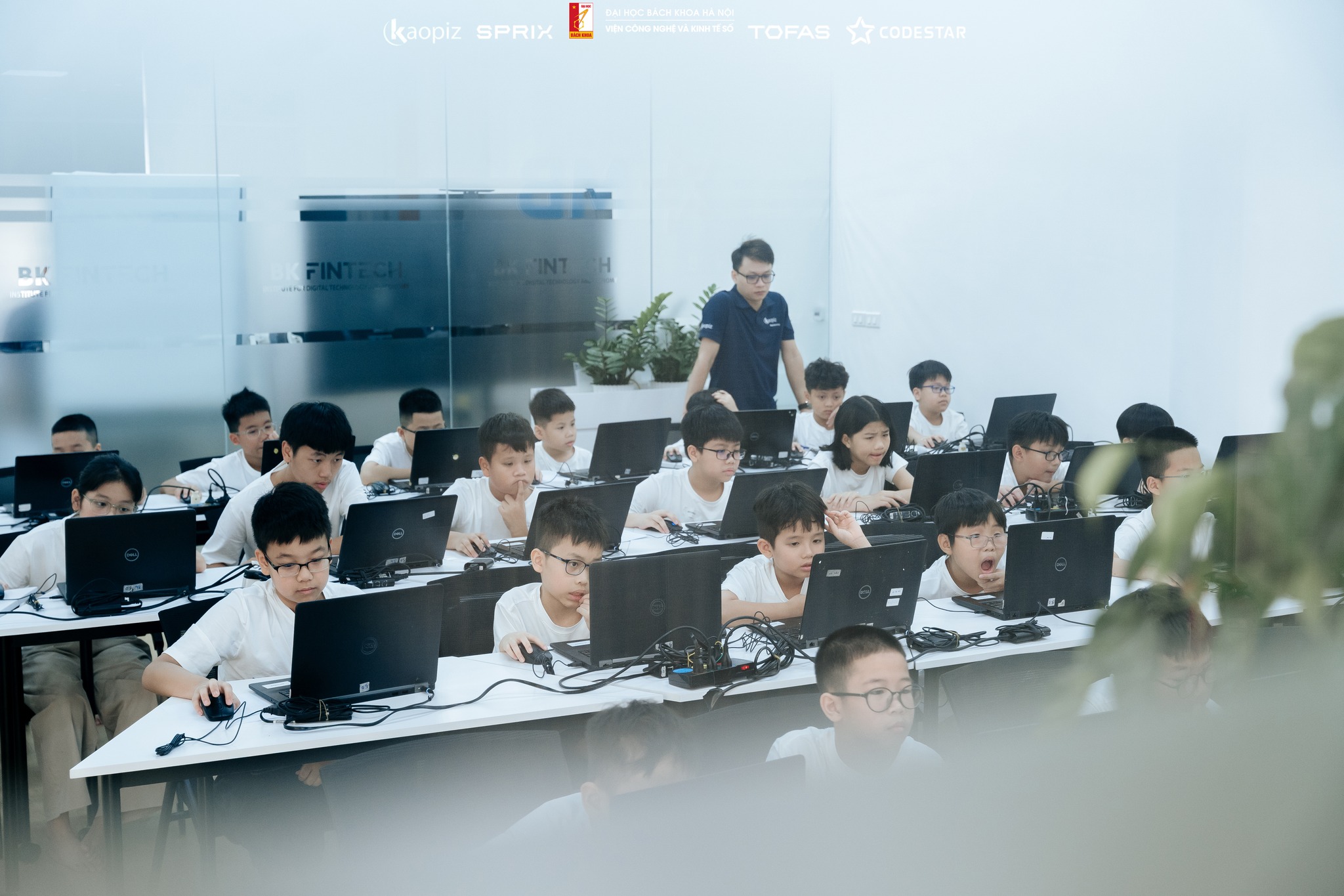 A young participant focused on solving a programming challenge on their laptop during the TOFAS 2025 finals.